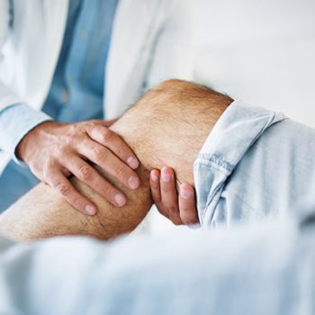 Médico traumatólogo evaluando la rodilla de un paciente en una consulta de Andes Salud.