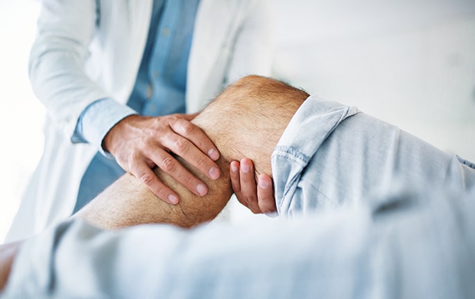 Médico traumatólogo evaluando la rodilla de un paciente en una consulta de Andes Salud.